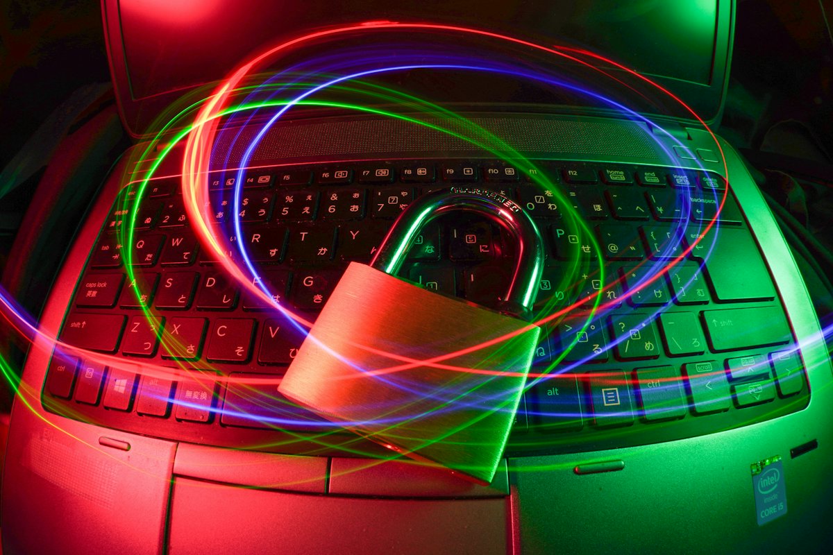 A padlock on a laptop keyboard with light trails across the screen