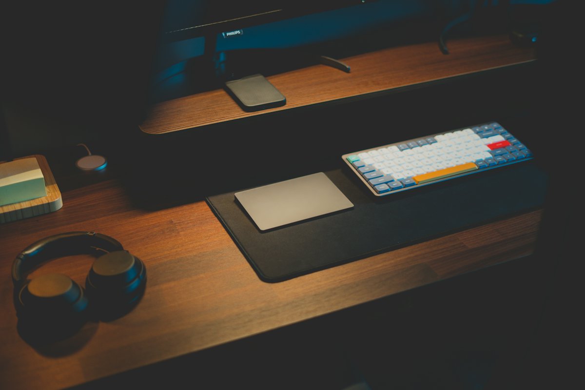 A hardware wallet resting beside its plain white packaging on a wooden desk